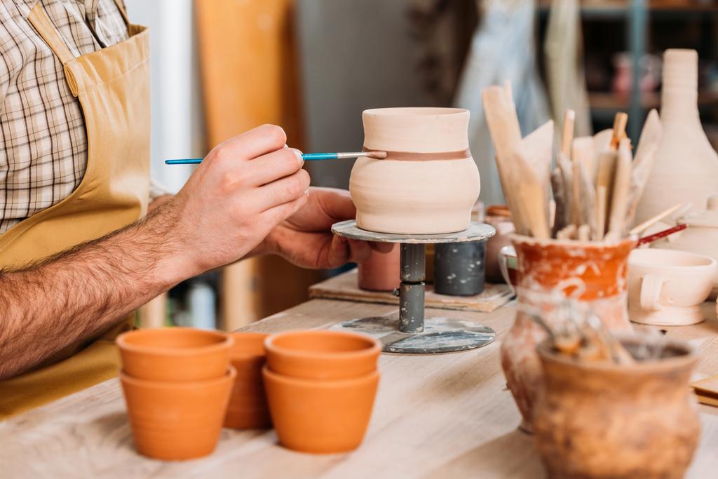 обрезанный вид гончарной живописи керамический кувшин с кистью в мастерской
 - Фото, изображение