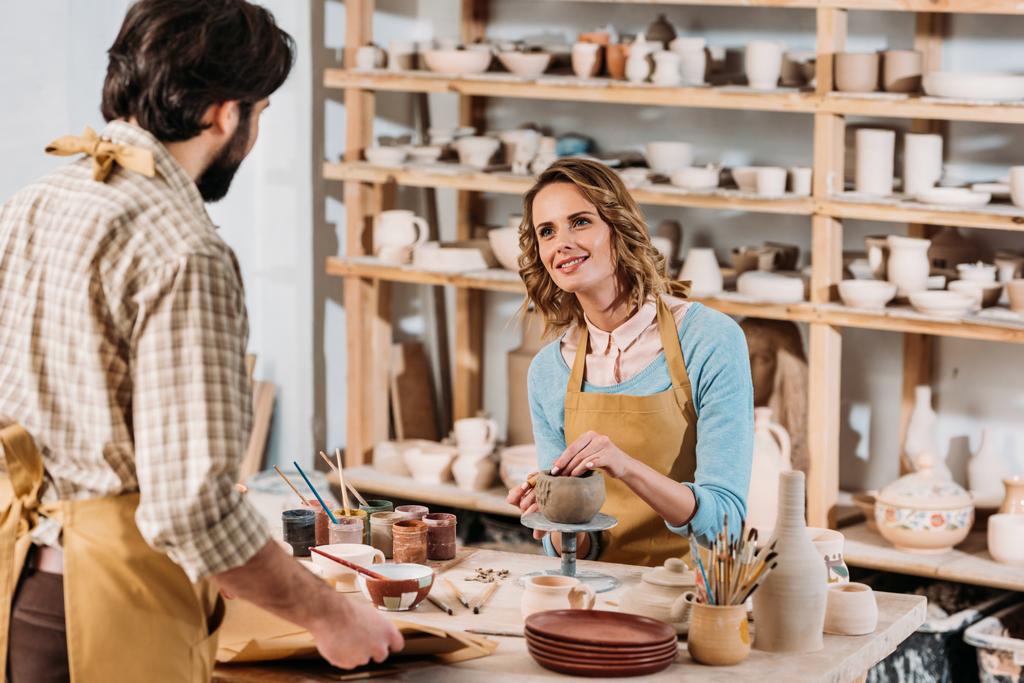 мужчина с бумагами и женщина гончар с керамикой в мастерской
 - Фото, изображение