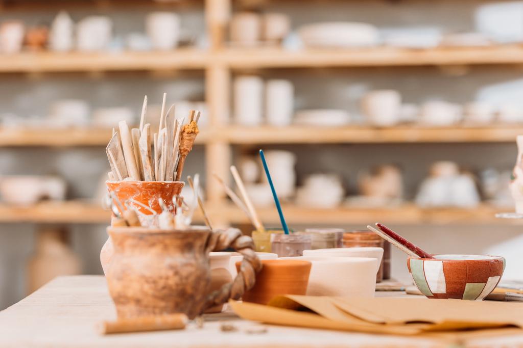 selective focus of ceramics and pottery tools on wooden table in workshop - Photo, Image