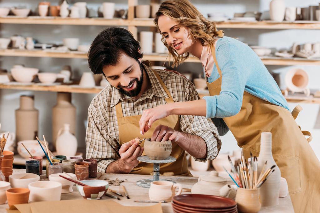 пара гончаров, делающих керамическую посуду вместе в мастерской
 - Фото, изображение