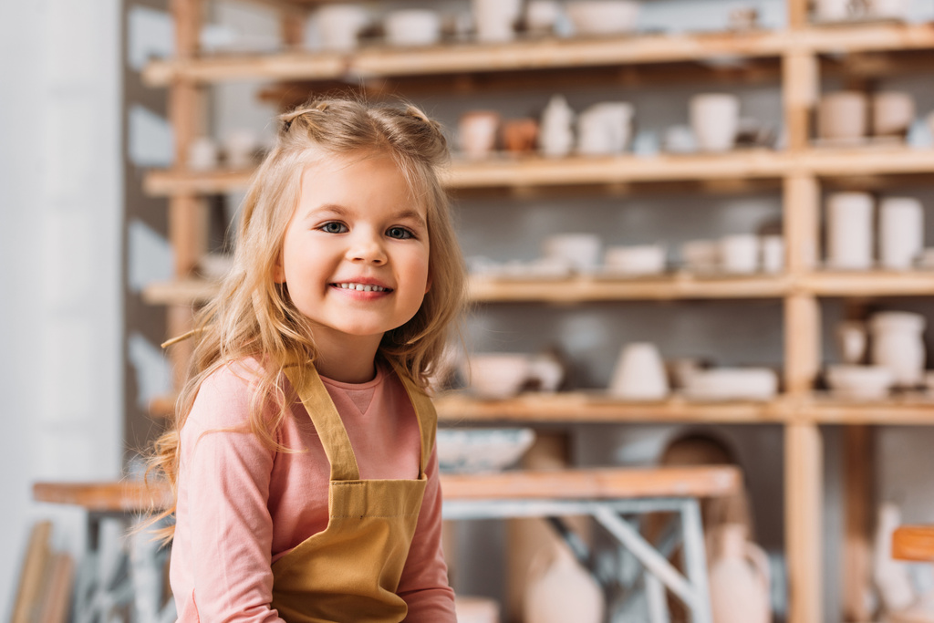 blonde souriant enfant regardant caméra dans poterie atelier
 - Photo, image