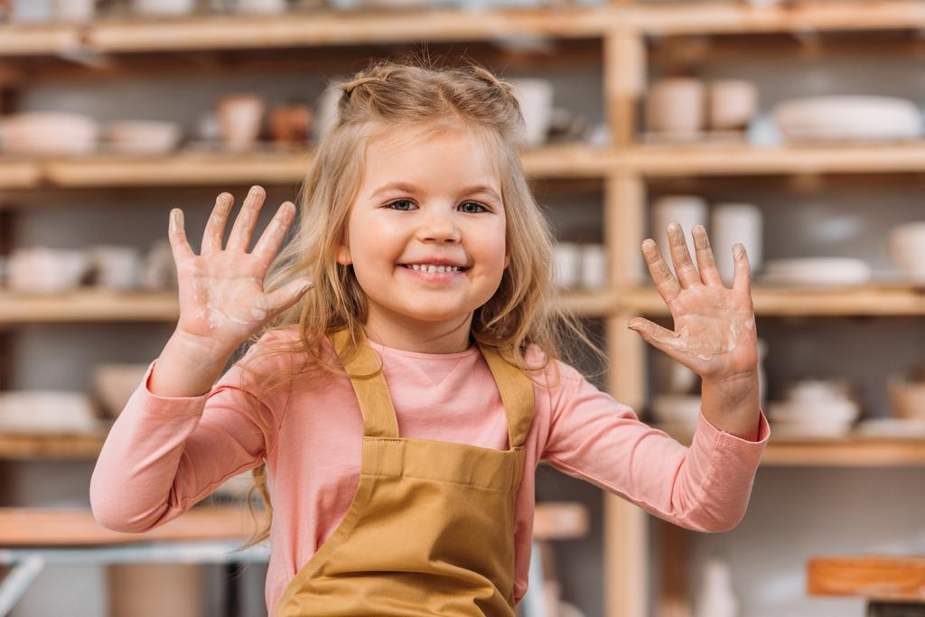 αξιολάτρευτο χαμογελαστό παιδί δείχνει τα χέρια σε πηλό   - Φωτογραφία, εικόνα