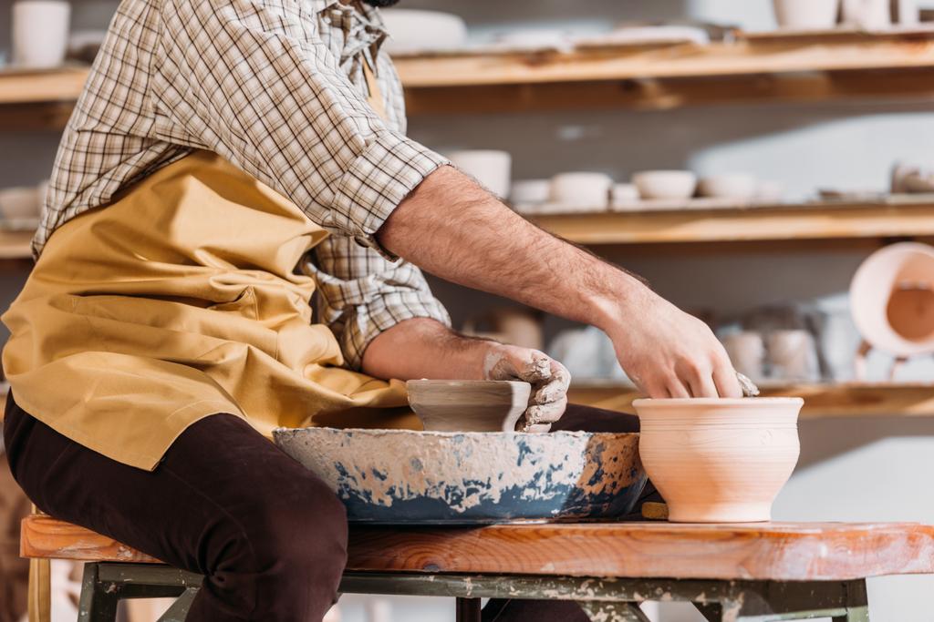 vista cortada do oleiro fazendo vasos de cerâmica na roda de cerâmica na oficina
 - Foto, Imagem