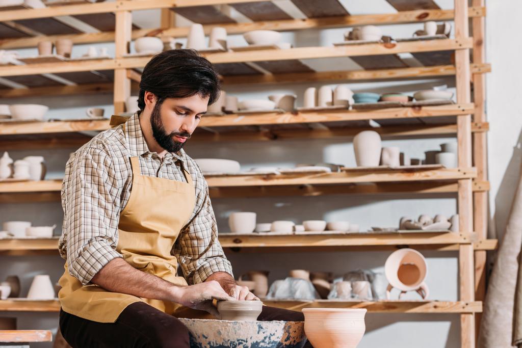 bebaarde man maken van keramische pot op aardewerk wiel in de pottenbakkerij - Foto, afbeelding