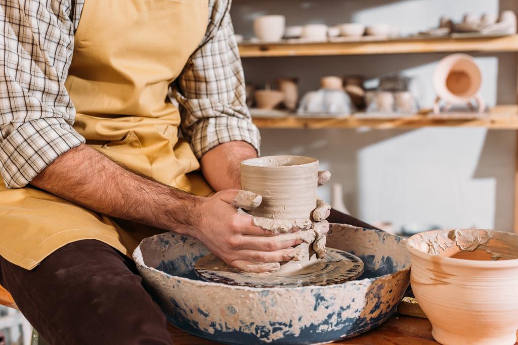 陶器のホイールに陶磁器の鍋で男性の手の部分ビュー   - 写真・画像