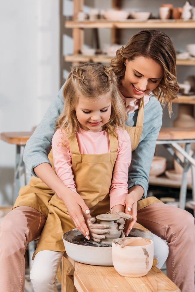teacher and kid making ceramic pot together on pottery wheel - Photo, Image