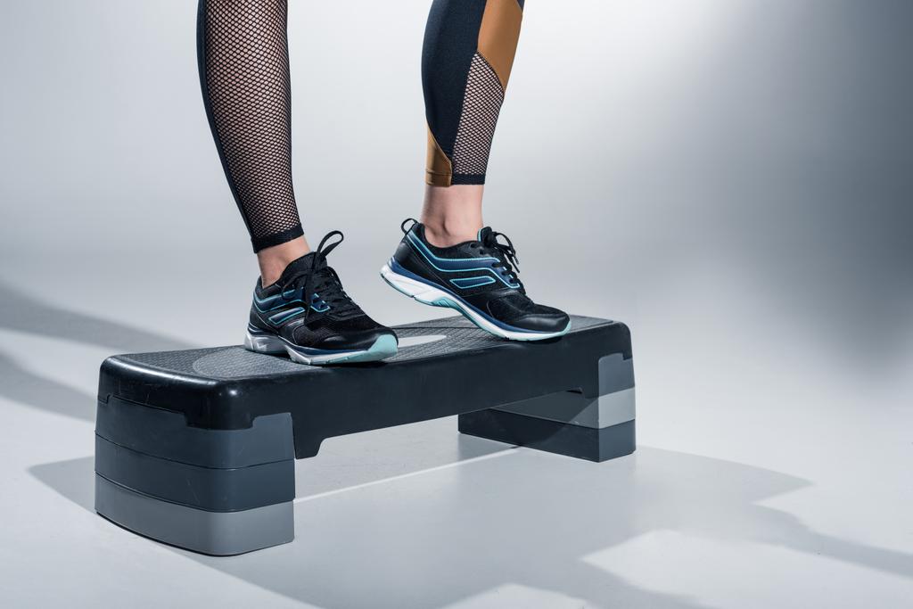Close-up view of woman training on step platform on grey background - Photo, Image