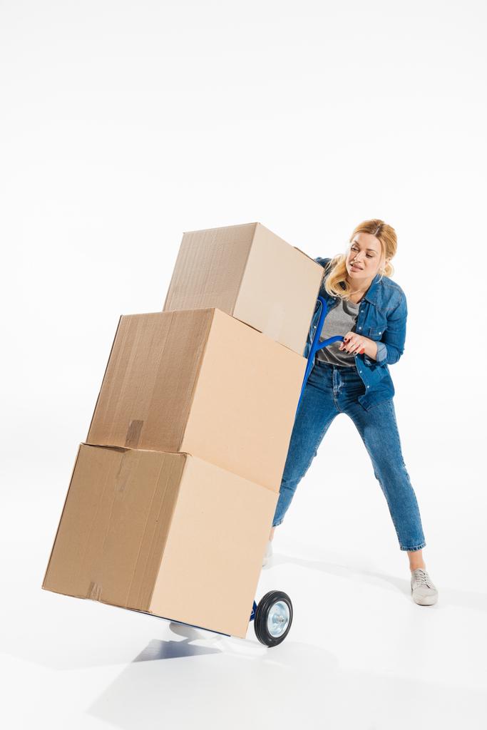 Donna attraente alle prese con carrello di consegna caricato con scatole isolate su bianco
 - Foto, immagini