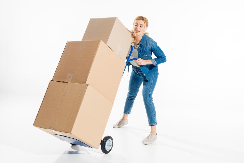 Giovane donna che tiene carrello caricato con scatole isolate su bianco
 - Foto, immagini