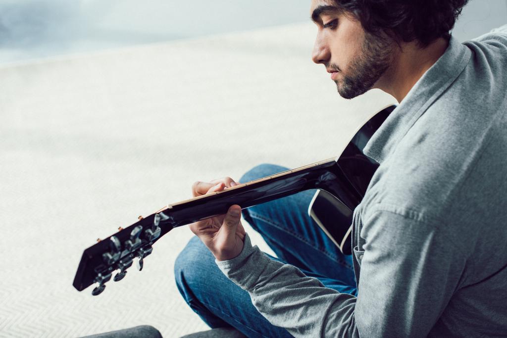 jóképű férfi játszik akusztikus gitár otthon - Fotó, kép