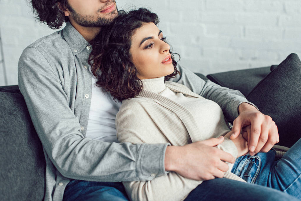 cropped image of young couple hugging on sofa at home - Photo, Image