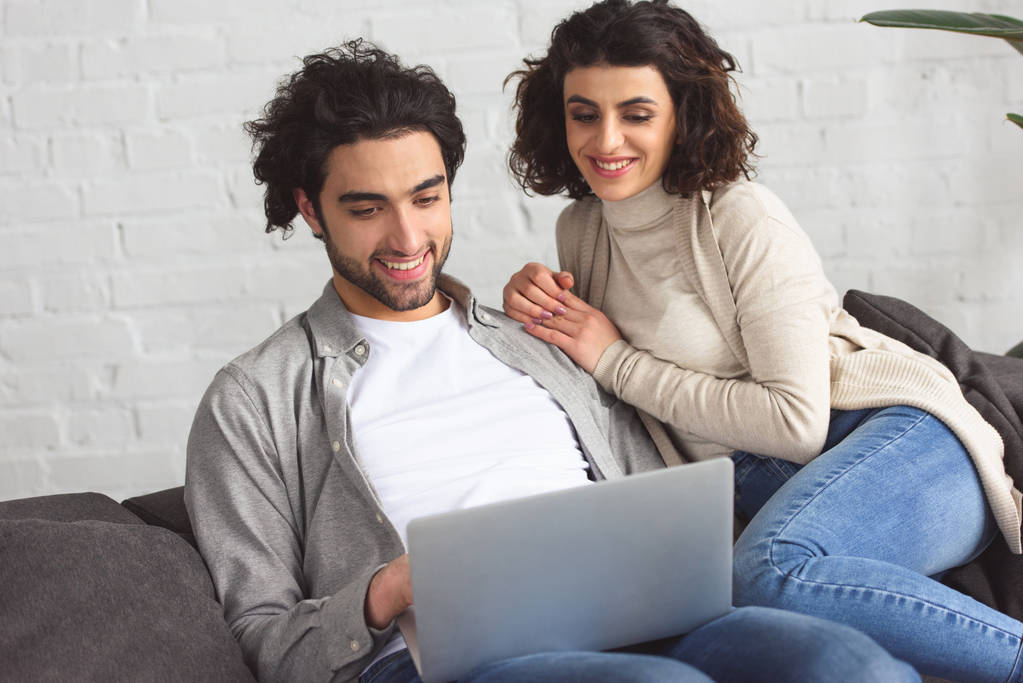 Lächelndes junges Paar schaut zu Hause auf Laptop - Foto, Bild