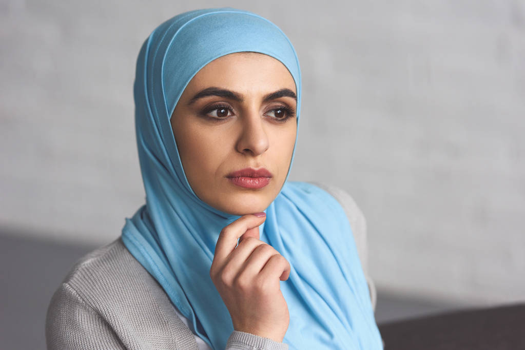portrait of pensive beautiful muslim woman in hijab looking away at home - Photo, Image
