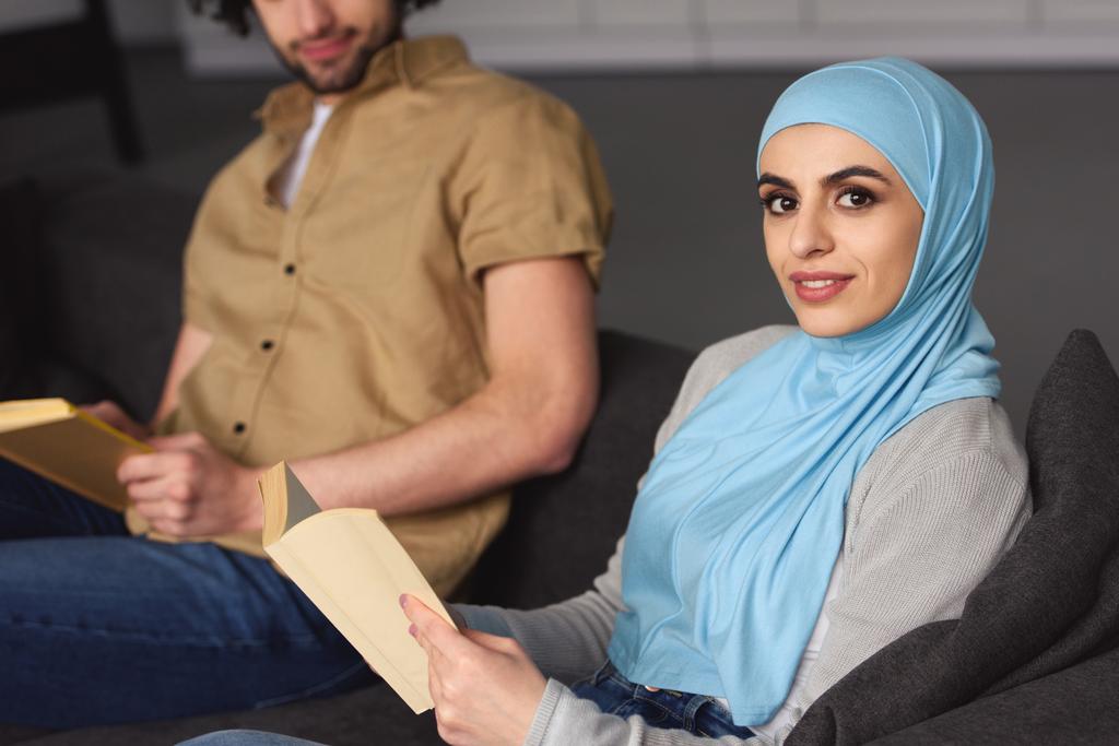 περικομμένη εικόνα της μουσουλμανικής ζευγάρι συνεδρίαση με τα βιβλία στο σπίτι - Φωτογραφία, εικόνα