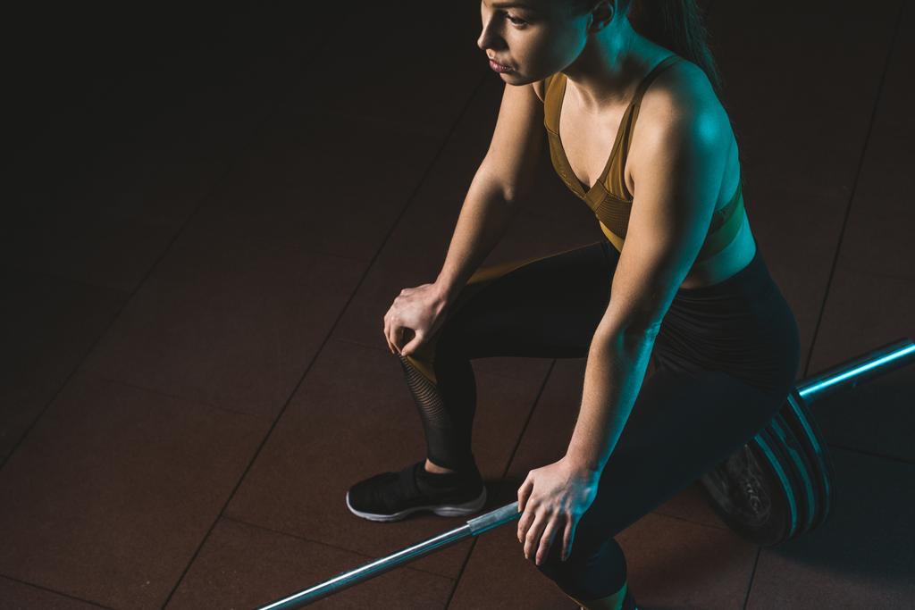 abgeschnittenes Bild einer jungen Sportlerin auf der Langhantel im Fitnessstudio - Foto, Bild