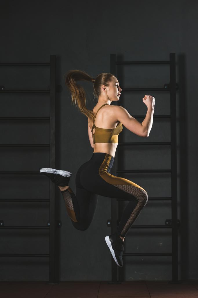 Vista lateral de salto esportista fazendo exercício cardio no ginásio
 - Foto, Imagem