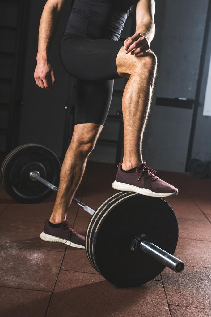 Cropped image of resting sportsman standing on barbell  in gym - Photo, Image