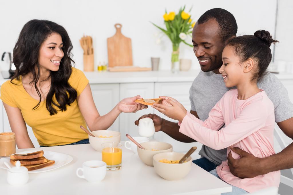 Улыбающаяся молодая семья вместе завтракает на кухне
 - Фото, изображение