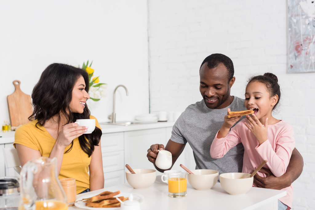 gelukkige jonge familie onder gezond ontbijt over keuken samen - Foto, afbeelding