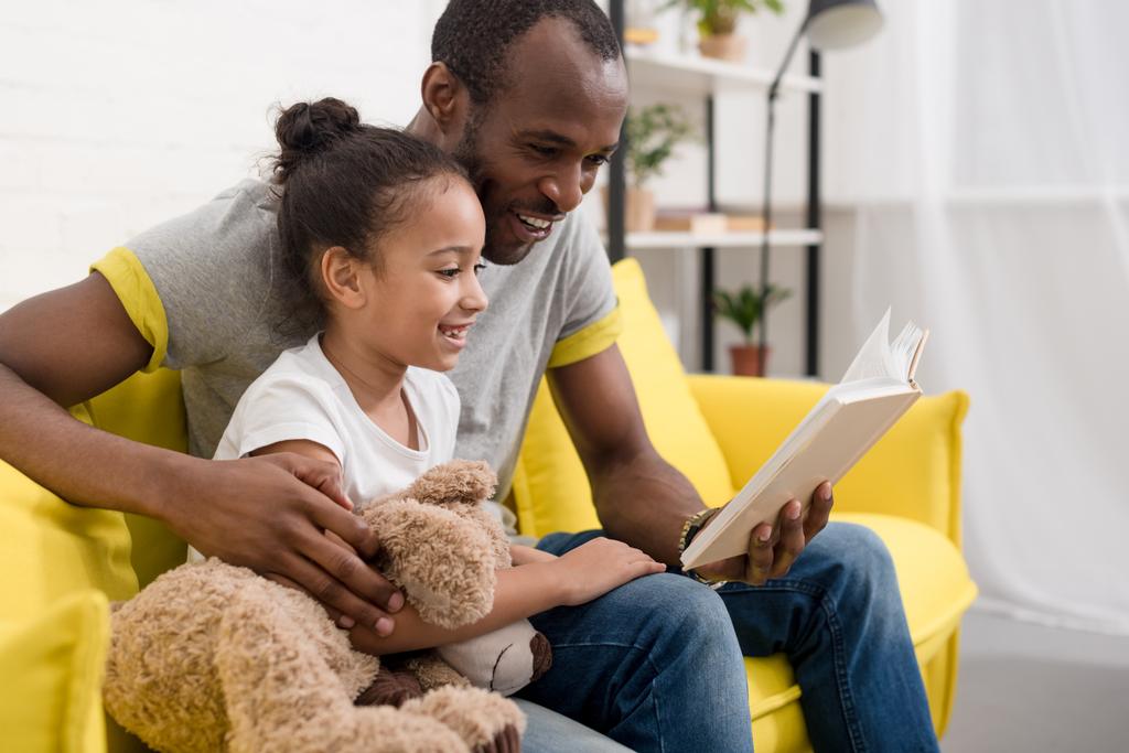 happy young father and daughter reading book together at home - Photo, Image