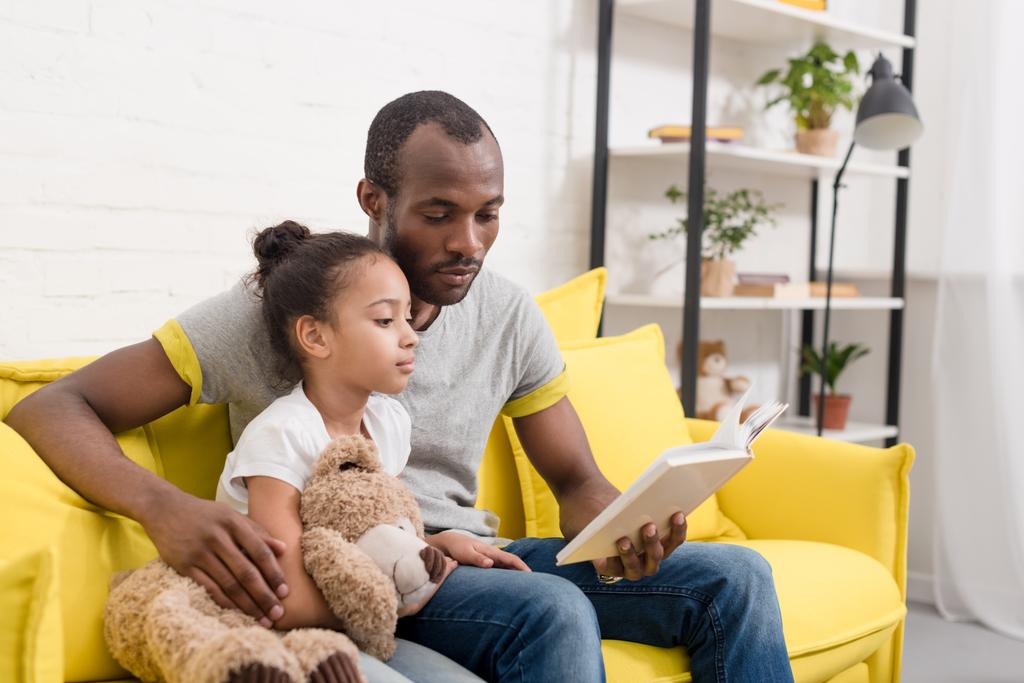 handsome father and little daughter reading book together at home - Photo, Image