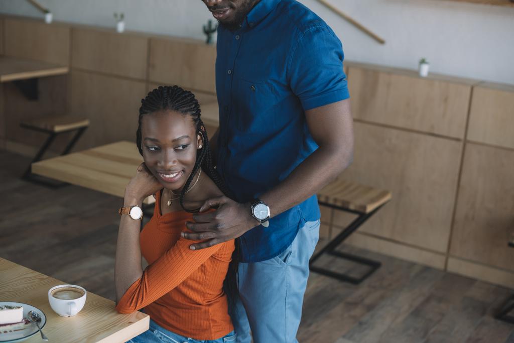 Часткове зору того, афроамериканці людина обійматися усміхнений подруга на романтичне побачення в кафе - Фото, зображення