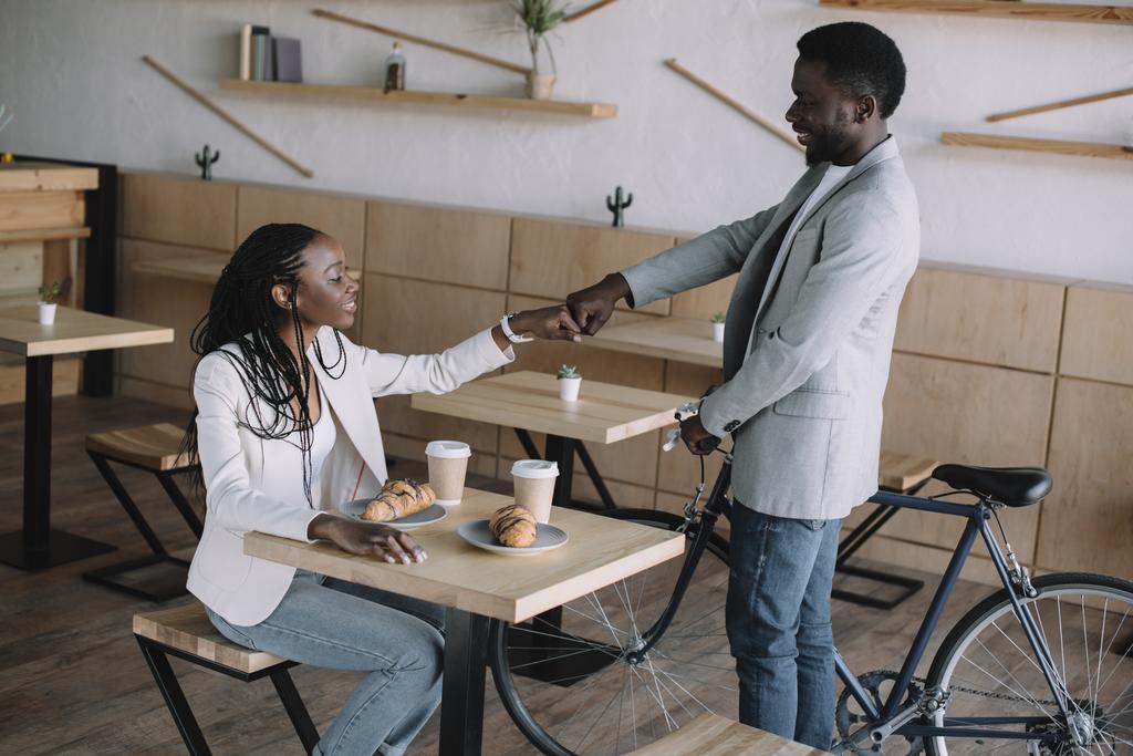 афроамериканські друзі вітають один одного за столом у кафе
 - Фото, зображення