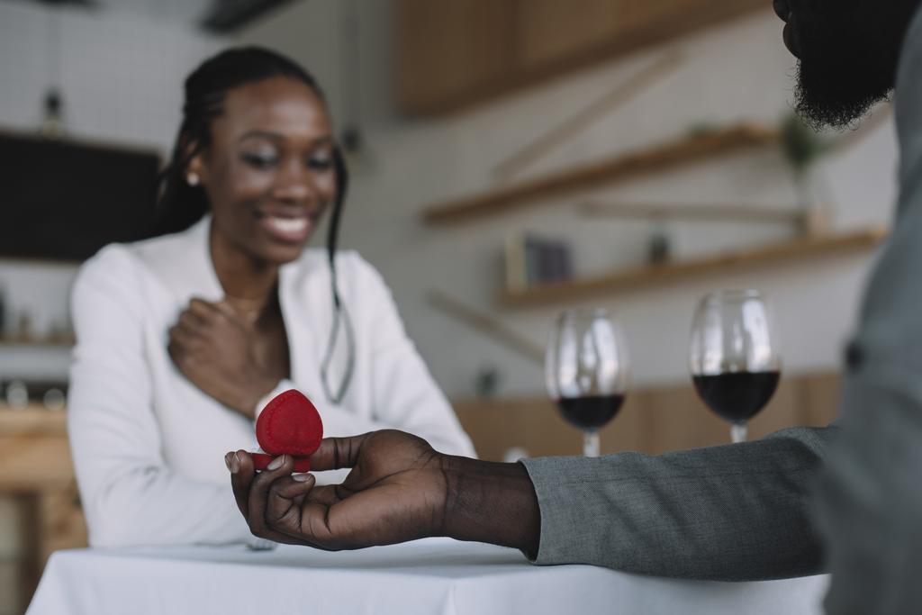 レストランでロマンチックな日付の間にガール フレンドに提案しているアフリカ系アメリカ人の部分的なビュー - 写真・画像