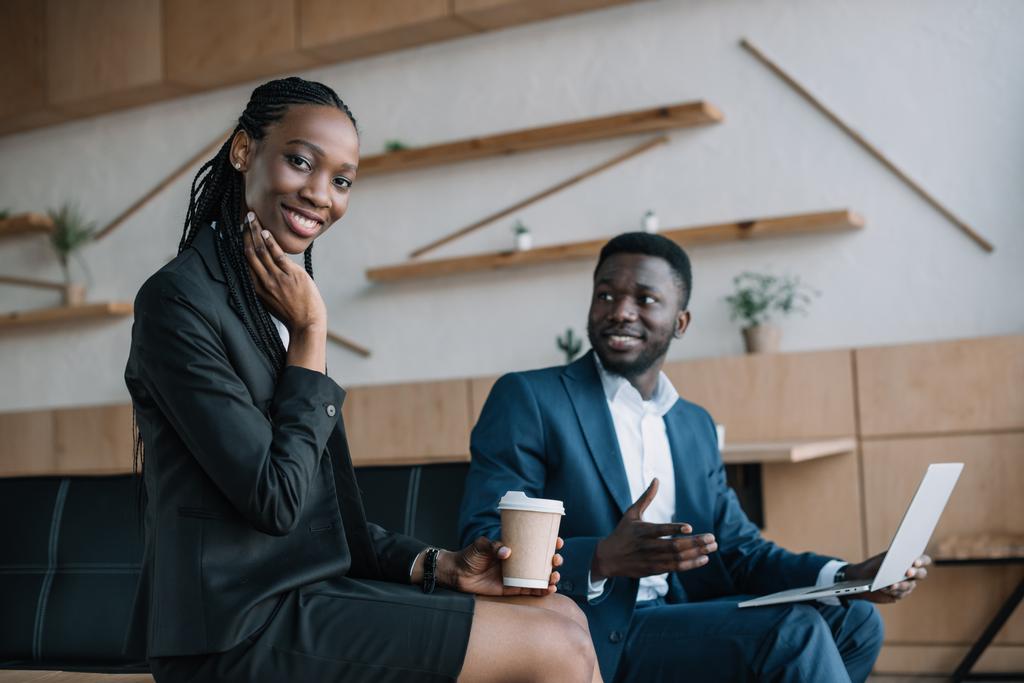 sorridente empresário afro-americano com laptop e colega com café para se aproximar no café
 - Foto, Imagem