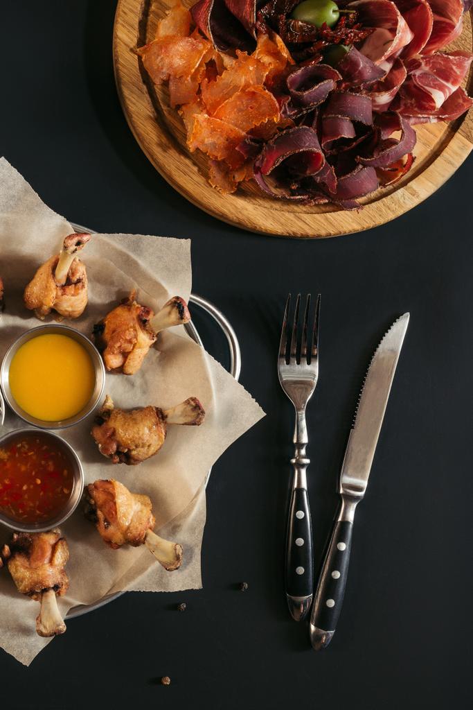 délicieux poulet rôti avec diverses sauces, viande gastronomique assortie et fourchette avec couteau sur noir
 - Photo, image