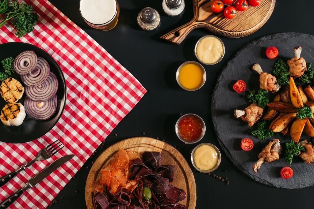 pohled shora gurmánské míchané maso, zeleninu, omáčky a pečené brambory pečené kuře na černém pozadí - Fotografie, Obrázek