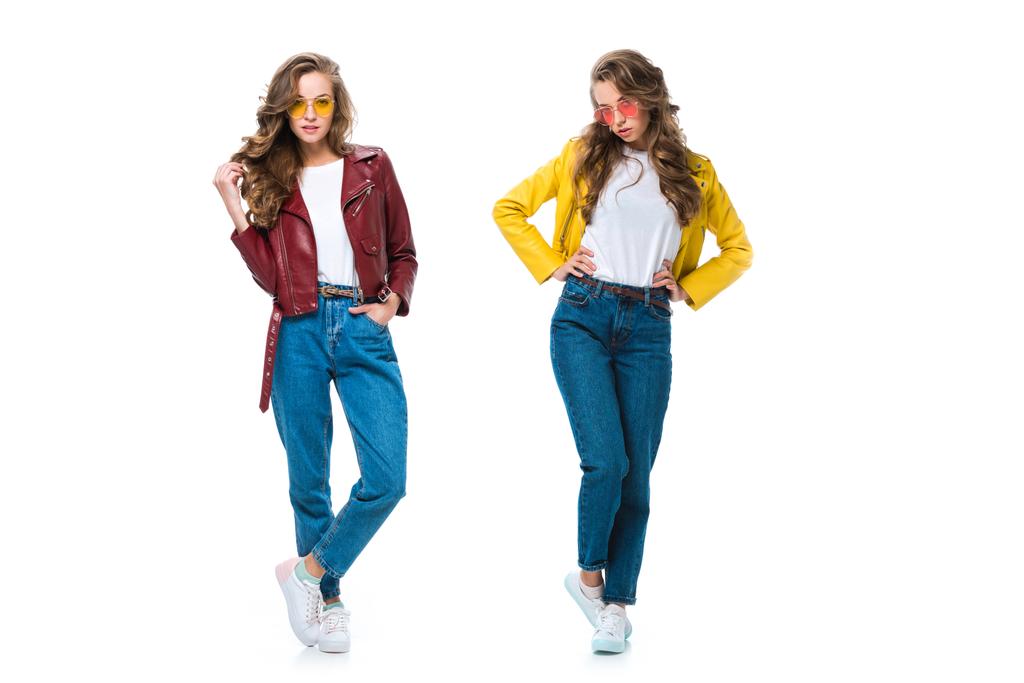 mooie stijlvolle tweeling in lederen jassen en zonnebrillen poseren geïsoleerd op wit - Foto, afbeelding