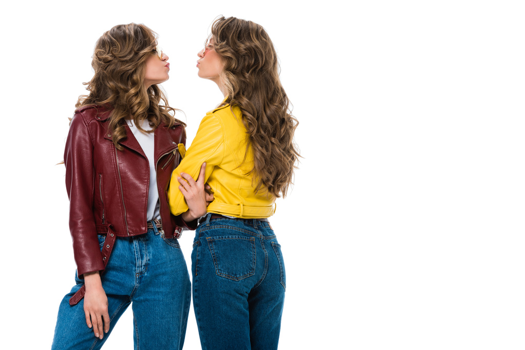 vista laterale di attraenti gemelli eleganti in giacche di pelle e occhiali da sole andando a baciare isolato su bianco
 - Foto, immagini