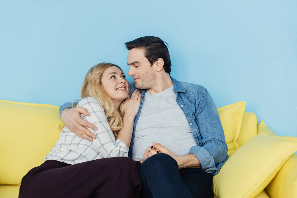 Romantyczna para siedzi i trzymając się za ręce na kanapie żółty - Zdjęcie, obraz