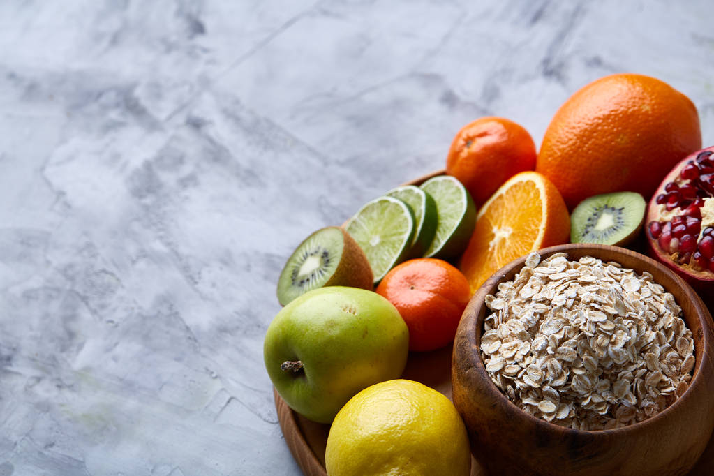 Kom met havermout vlokken geserveerd met fruit op houten dienblad op witte achtergrond, plat lag, selectieve aandacht - Foto, afbeelding