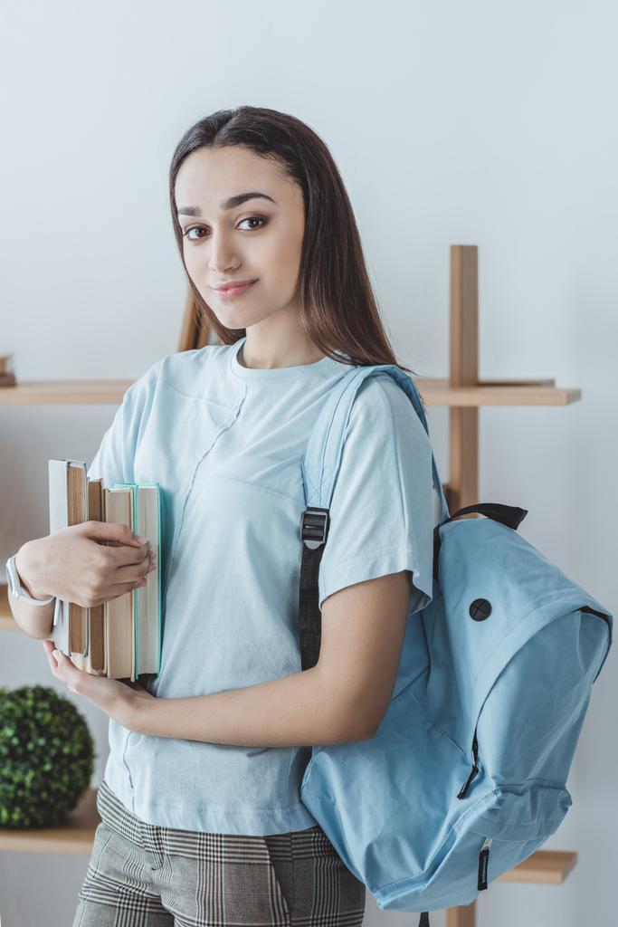 beautiful mixed race girl with backpack holding books  - Photo, Image
