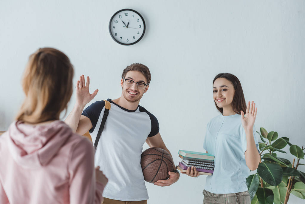 jóvenes estudiantes con libros y baloncesto saludando a su amigo
 - Foto, imagen