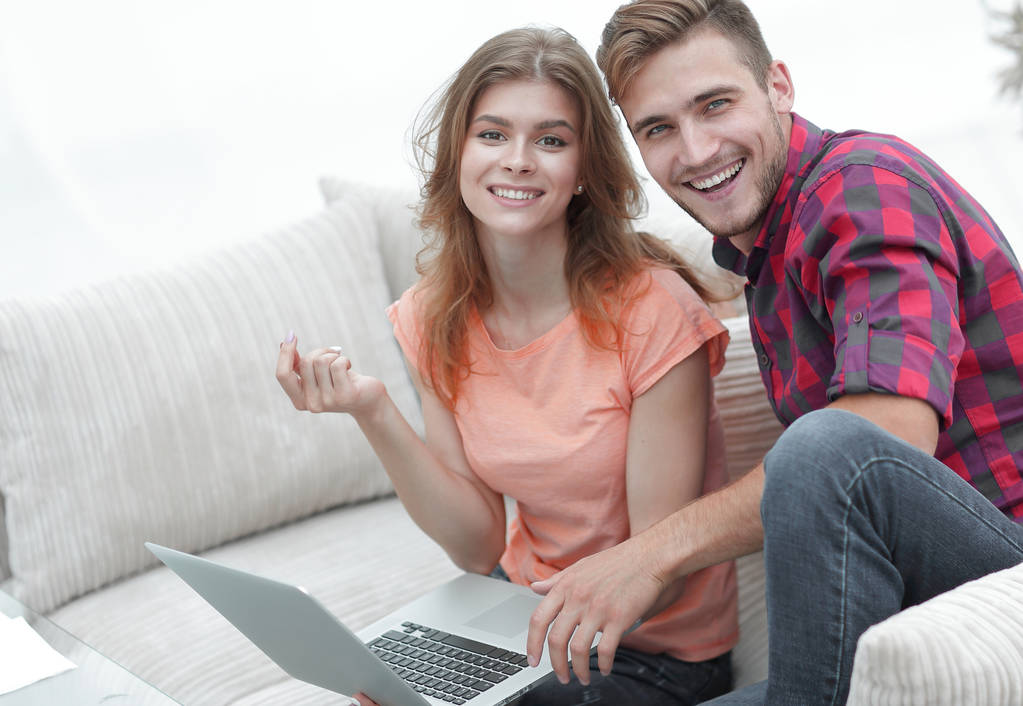 pair students with a laptop sitting on sofa - Photo, Image