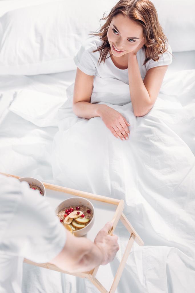 vista parcial del hombre trajo el desayuno en la cama para la novia sonriente
 - Foto, Imagen