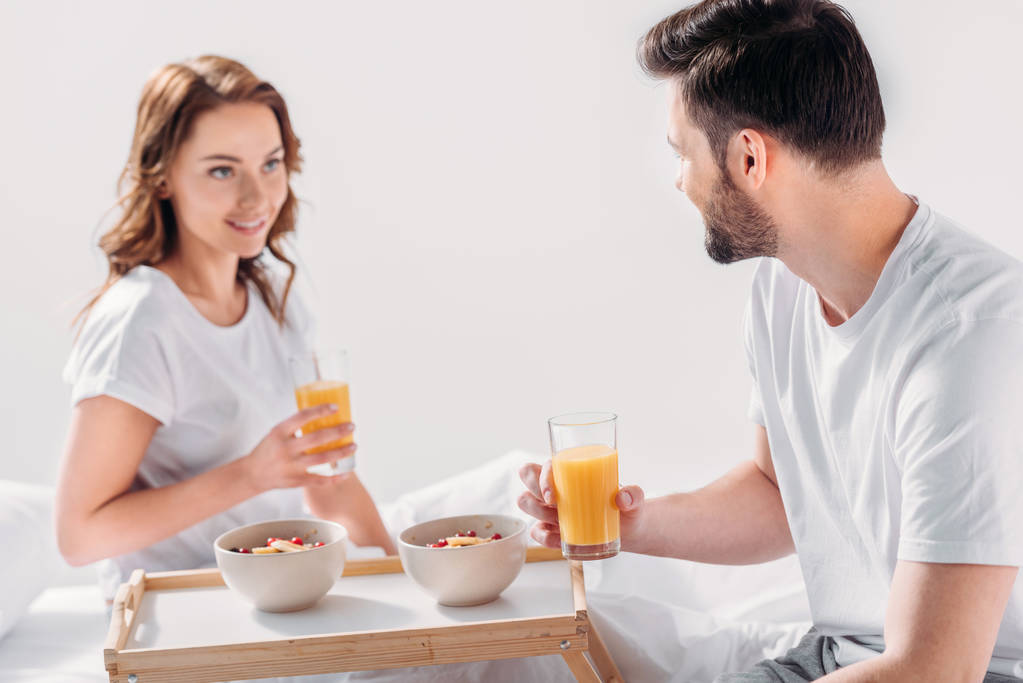 朝一緒にグレーの分離でベッドでの朝食を持っている若いカップル - 写真・画像