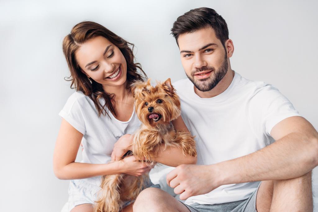 portrait of young smiling couple with yorkshire terrier isolated on grey - Photo, Image