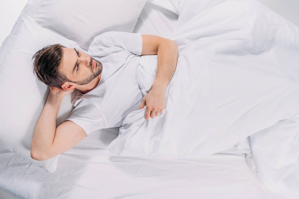 yleisnäkymä mietteliäs parrakas mies katselee pois nukkuessaan sängyssä
 - Valokuva, kuva