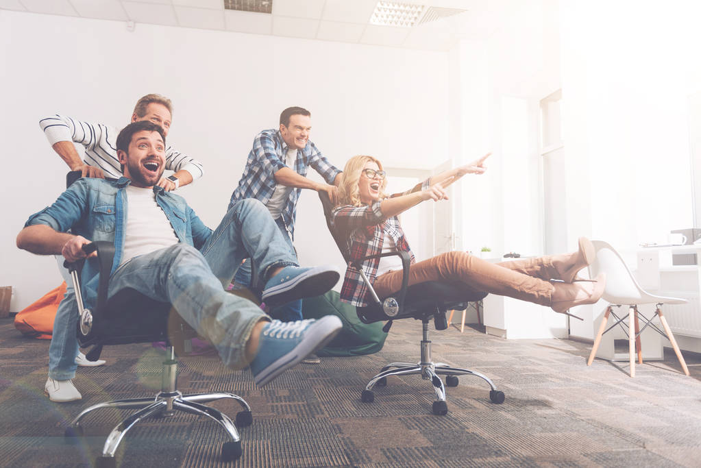 Compañeros alegres divirtiéndose en sillas de oficina
 - Foto, imagen