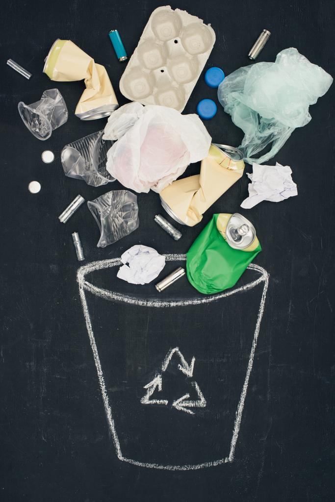 varios tipos de basura que cae en la papelera dibujada con el cartel de reciclaje en la pizarra
 - Foto, Imagen