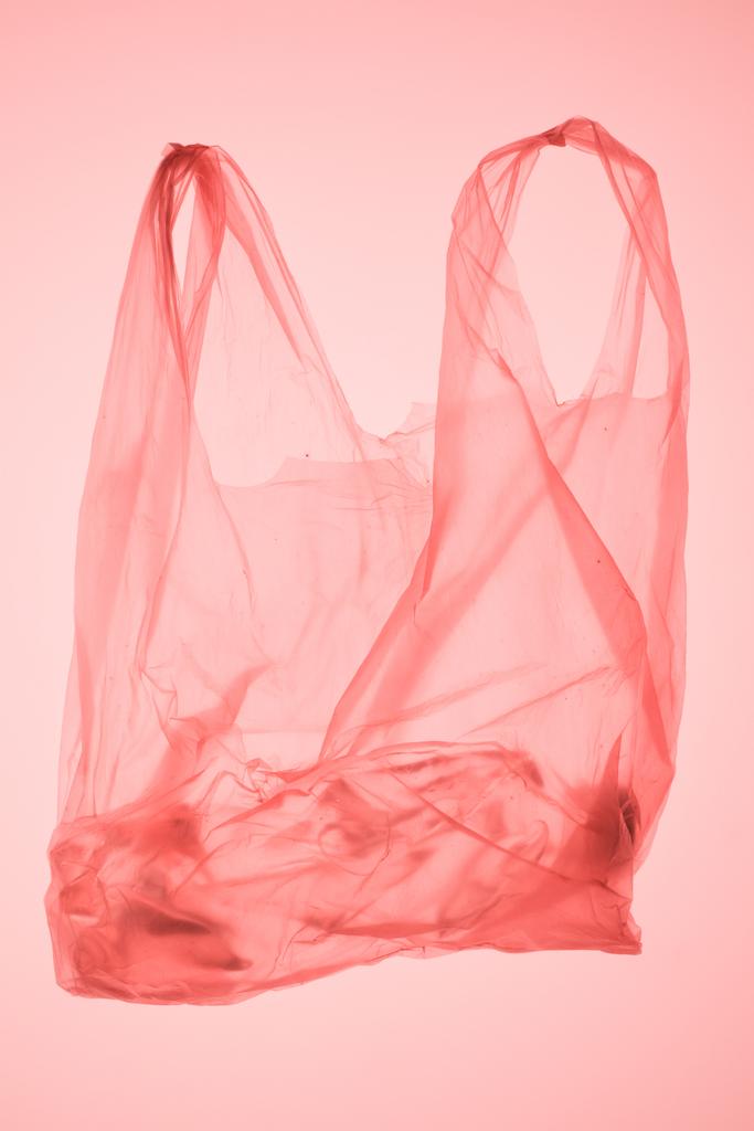 verfrommeld kunststofzak met fles binnen onder pastel roze getinte licht - Foto, afbeelding