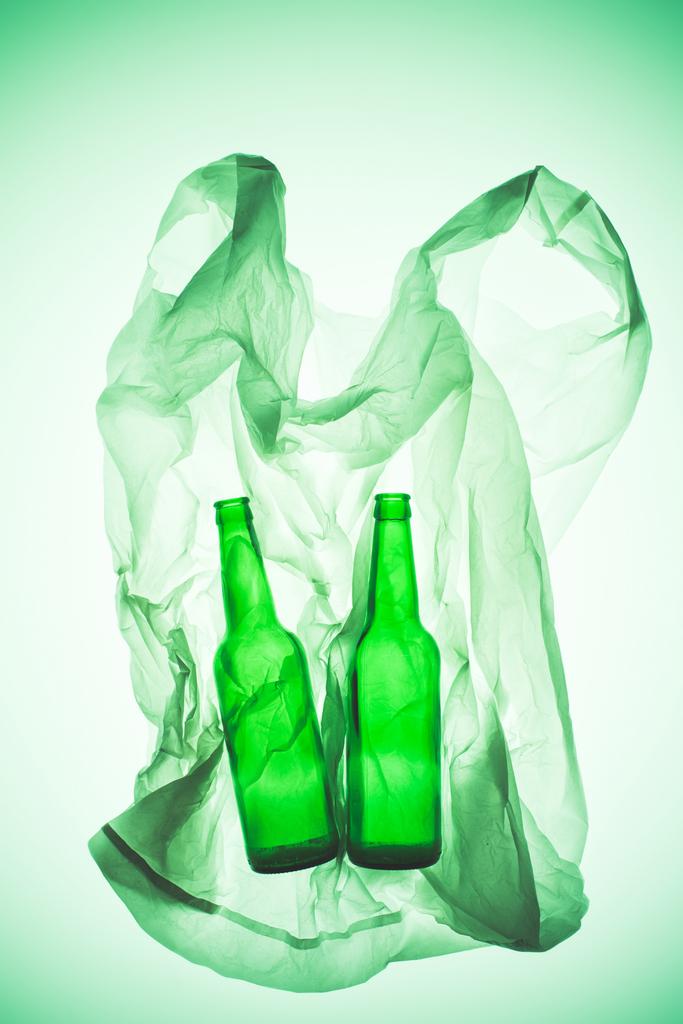 crumpled plastic bag with glass bottles under green toned light - Photo, Image