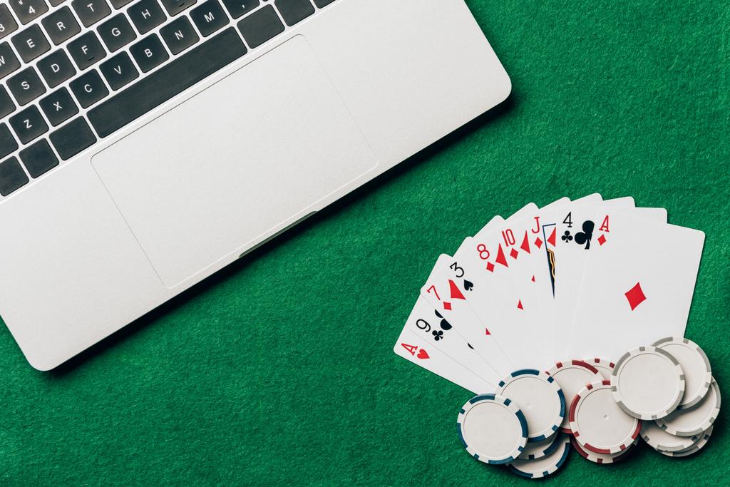 Hrací karty a čipy na kasino tabulky pomocí notebooku - Fotografie, Obrázek