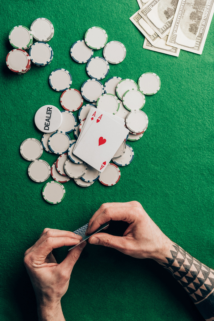 Mann hält Pokerkarten am Casino-Tisch mit Chips - Foto, Bild
