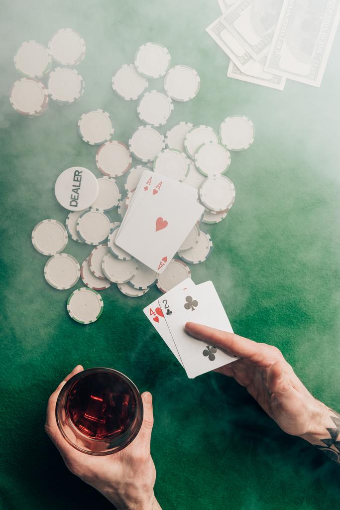 Человек с виски и покерными картами за столом казино
 - Фото, изображение