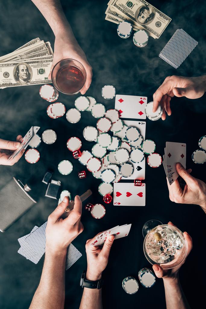 Smoke over people with alcohol in glasses playing poker by casino table with money and chips - Photo, Image